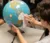 A student holds a paper cut out of the shape of Africa in front of a globe