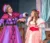 two female students dressed in costumes perform on stage