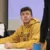 Young man in yellow sweatshirt looks up from desk in classroom