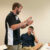 Professor uses hands to explain notes on the whiteboard to a sitting male student
