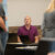 A man in a purple shirt looks up at a man in a gray shirt
