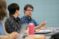 A male student gestures as he speaks in class