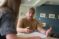 A male student talks over a notebook with another student