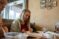 a girl sits at a table and reviews a paper