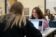 two students talk over their laptops and books at a table in class