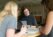 Three female students sit around a table with their laptops and textbooks