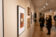 People admire pictures hung up on the wall of the art exhibit