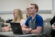 male student pays attention in class while taking notes on his mac laptop