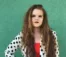 A picture of a women wearing a black and white polka-dot jacket with long brown hair