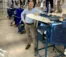 A picture of a man in a light blue shirt standing next to machinery