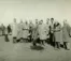 An old photo of a group of men in trench coats, with one digging a hole