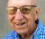 A picture of an elderly man with glasses, wearing a blue plaid shirt