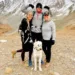A picture of a international student with two members of his host family and a dog posing for a picture in the mountains