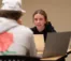Female student looks up and discusses something with male student across from her in class