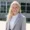 Blond-haired young woman in sport coat smiling in front of building
